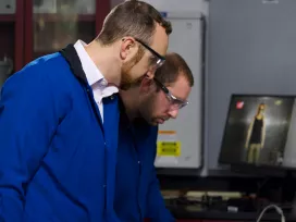 Two engineers in safety glasses engaged in a battery performance test. Exponent engineers assist with battery safety and recall support