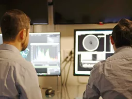 Worker scans images and videos on computer screens. Exponent engineers provide support for computer control systems.