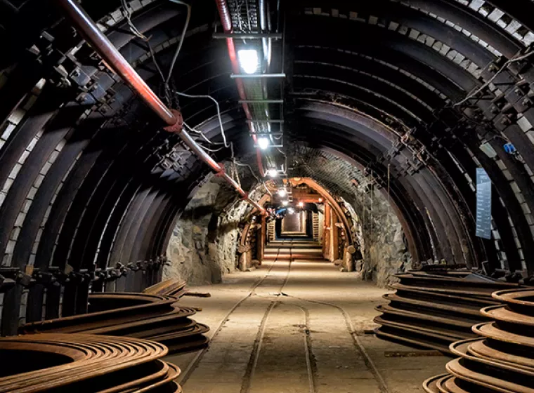 The inside of a coal mine, a brightly lit tunnel with a wooden pathway. Expertise to improve efficiency and safety of forestry and mining.