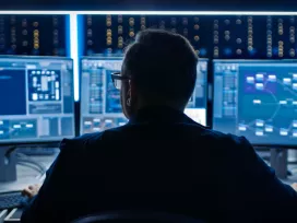 Worker scans images and videos on computer screens. Exponent engineers provide support for computer control systems.