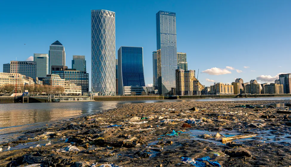 A Thames beach filled with waste and discarded flotsam at Rotherhithe across from Canary Wharf.