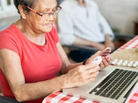 Patient looking over their prescriptions while sitting in front of a laptop