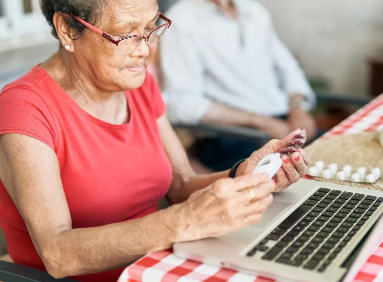 Patient looking over their prescriptions while sitting in front of a laptop