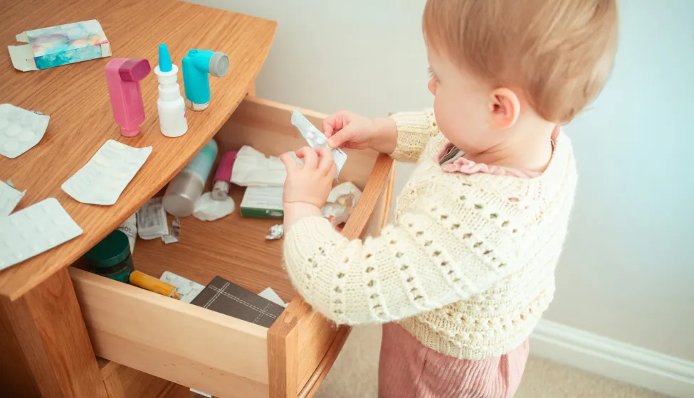 Toddler looking through a bedside cabinet full of prescription medicines