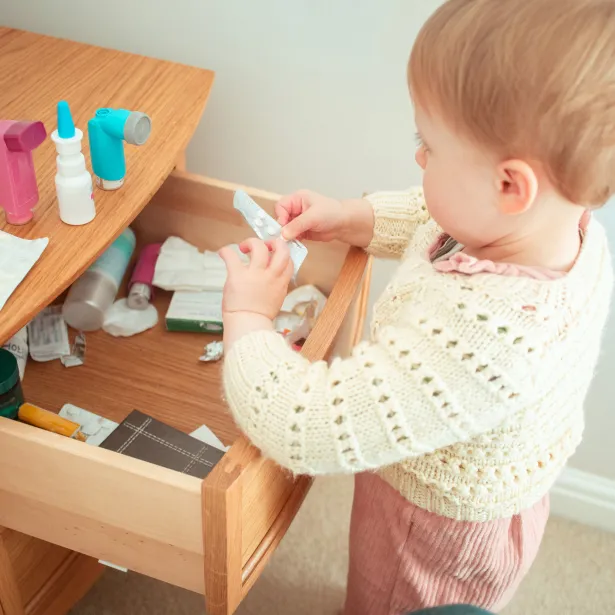 Toddler looking through a bedside cabinet full of prescription medicines