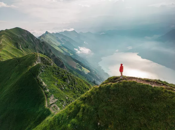 Aerial view of woman standing on top of the mountain ridge 