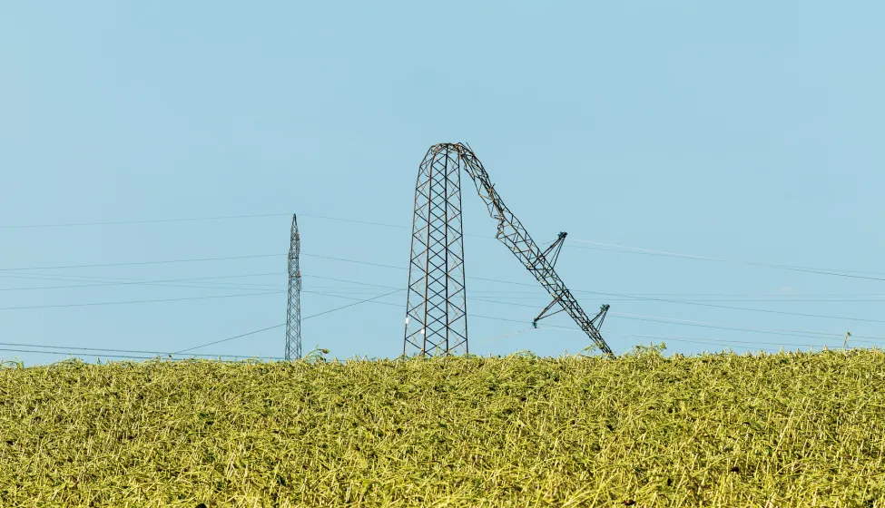 Bent over electricity pylon after strong summer storm, climate change consequences