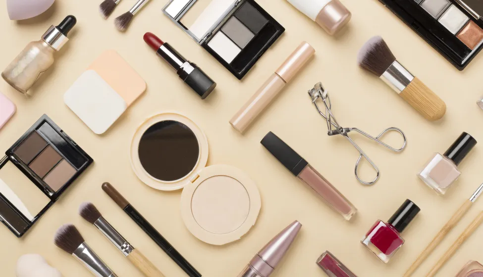 Flat lay with makeup products and tools on color background