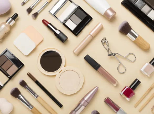 Flat lay with makeup products and tools on color background