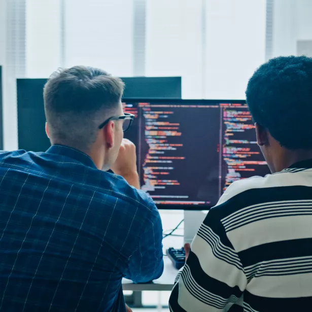 software developers meeting on multiple computer screens displaying programming code