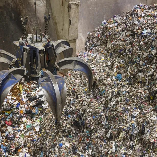 Mechanical claw hand grabbing pile of mixed waste