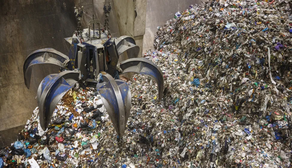 Mechanical claw hand grabbing pile of mixed waste