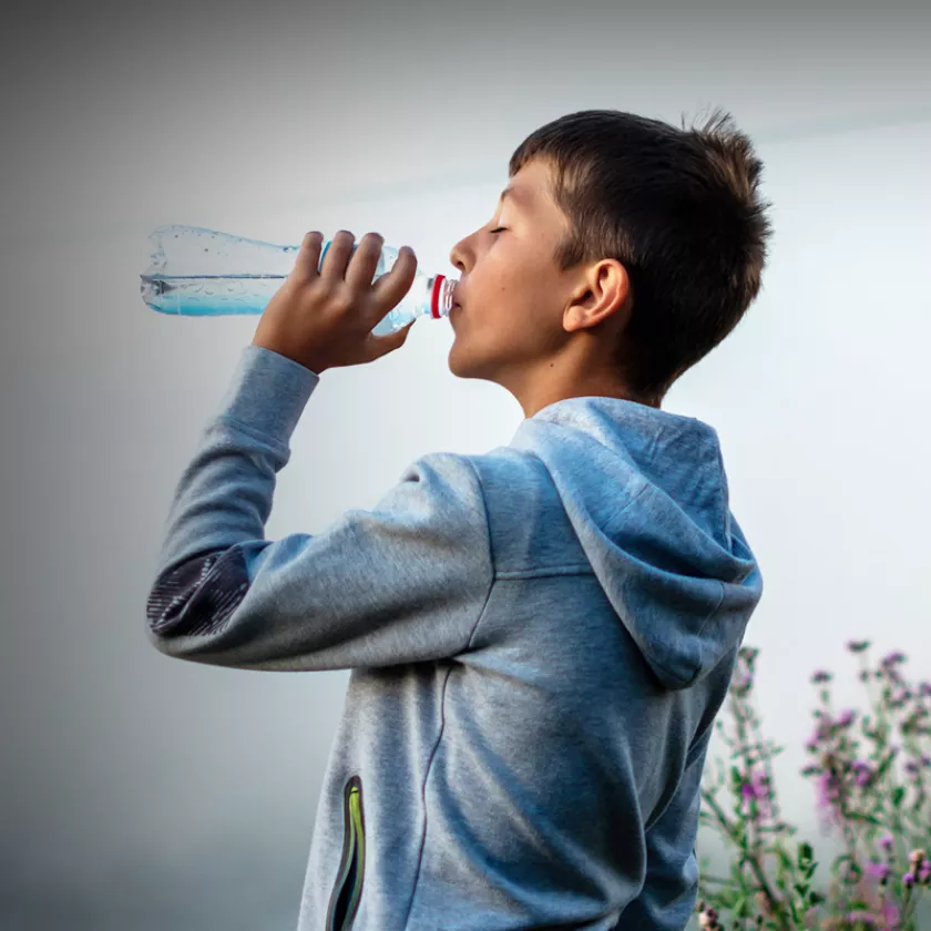 Youth drinks from a plastic water bottle. Exponent supports product development to improve safety and performance of products.