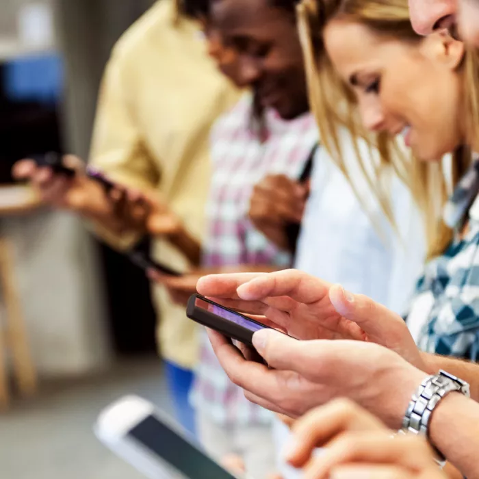 A group of young adults on phones. Exponent provides scientific and engineering expertise for consumer electronics and products.