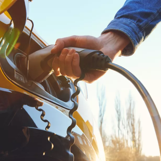 A person plugs in an electrical vehicle for charging