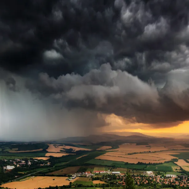 Aerial view of dark brooding storm clouds with lightening passing over urban development and open fields