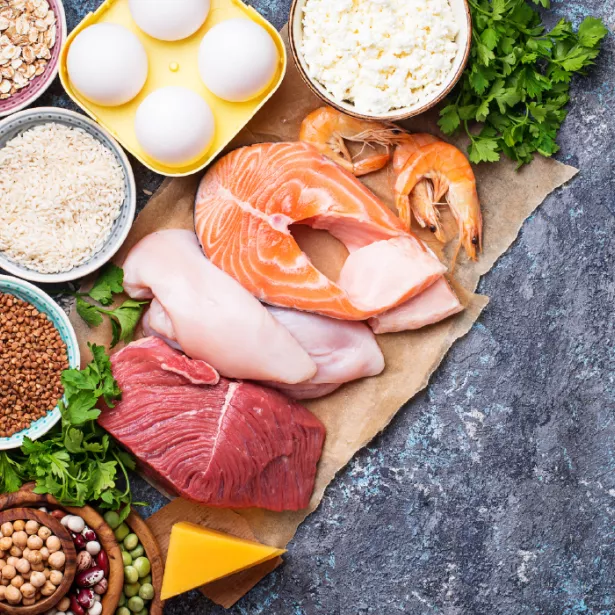 Carving board featuring an array of raw meat, vegetables, nuts, grains, and dairy foods